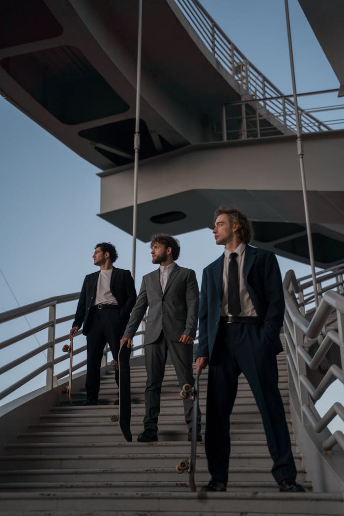 Three men in suits carrying skateboards on stairs under modern architecture.