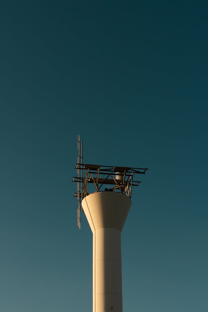 A sleek communication tower designed for industrial usage, silhouetted against a clear sky.